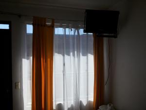 ventana con cortinas y TV en una habitación en Residencial Las Palmeras, en Iquique