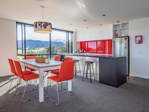 uma cozinha com armários vermelhos e uma mesa com cadeiras em Huia Box House - Ohakune Holiday Home em Ohakune