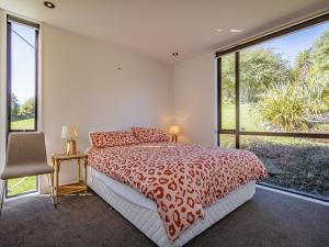 um quarto com uma cama e uma grande janela em Huia Box House - Ohakune Holiday Home em Ohakune