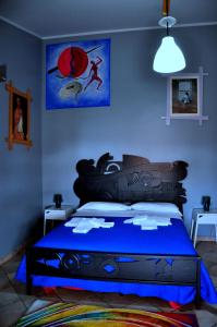 1 dormitorio con 1 cama con una pintura en la pared en Cinisi 89 B&B en Cinisi