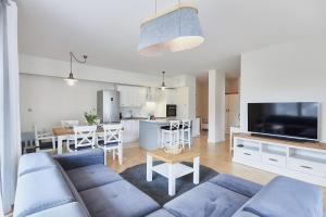 Il comprend un salon avec un canapé bleu et une cuisine. dans l'établissement Apartament Familijny Golden, à Międzyzdroje