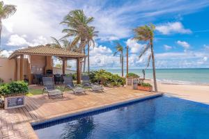 - une piscine à côté d'une plage bordée de palmiers dans l'établissement Varandas do Mar Condomínio Moderno por Carpediem, à Caucaia