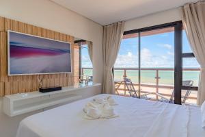 - une chambre avec un lit, une télévision et un balcon dans l'établissement Varandas do Mar Condomínio Moderno por Carpediem, à Caucaia