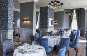 a restaurant with white tables and blue chairs at The Grand Hotel in Eastbourne