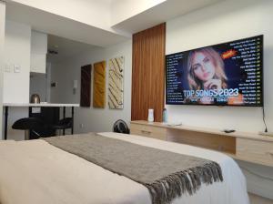 Schlafzimmer mit einem Bett und einem TV an der Wand in der Unterkunft Skycourt Suites at Azure North Pampanga Condominium in San Fernando