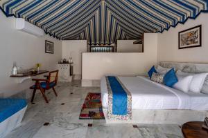 ein Schlafzimmer mit einem Bett mit einer blau-weißen gestreiften Decke in der Unterkunft Aangan Resort Ranthambhore - A Private Pool Villa in Khilchīpur