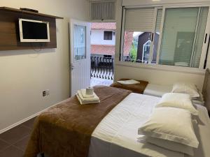 a bedroom with a large bed with a tv on the wall at Hotel Villa Deifiori in Bento Gonçalves