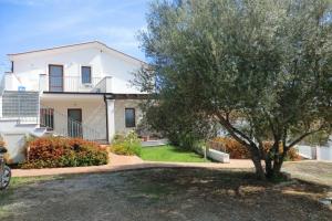 ein weißes Haus mit einem Baum davor in der Unterkunft I Girasoli in Bari Sardo