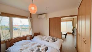 a bedroom with a bed and a large window at BBQ & Rental Villa Palm Village in Minamiboso