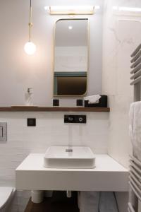 a white bathroom with a sink and a mirror at Hotel de la Poste in Corps