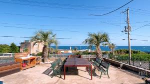 a patio with a wooden table and chairs and the ocean at BBQ & Rental Villa Palm Village in Minamiboso