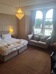 a bedroom with a bed and a couch and a chandelier at Heathcliff House B&B Exclusively for Adults Free large carpark in Torquay
