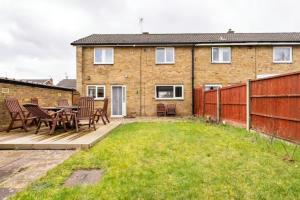 un patio con mesa y sillas frente a una casa en Stevenage Contractors x8 New 3 bedroom House Free Wifi, Parking, Towels all inclusive & Large Garden en Stevenage