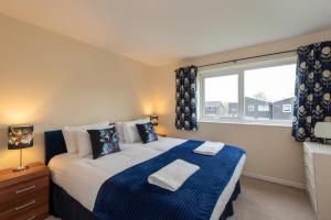 a bedroom with a bed with blue and white sheets and a window at Aysgarth Close in Newton Aycliffe