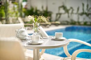 a table with a vase of flowers on it next to a pool at Villa Pinia Eco-hotel in Odesa