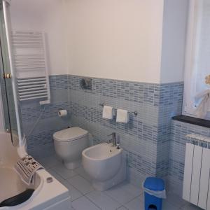 La salle de bains est pourvue de carrelage bleu, de toilettes et d'un lavabo. dans l'établissement Baita Milgra, à Riccò del Golfo di Spezia