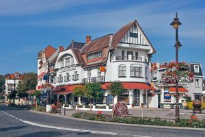 un grand bâtiment blanc au bord d'une rue dans l'établissement Holiday Suites De Haan, au Coq