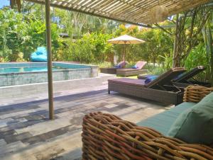 um pátio com cadeiras, um guarda-sol e uma piscina em Villa Jeruk em Selong Blanak