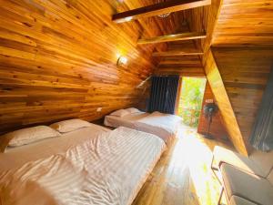 two beds in a room with wooden walls at Cat Ba Love House in Cat Ba