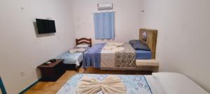 Habitación pequeña con 2 camas y TV. en Casa do Galego no Residência Família en Canoa Quebrada