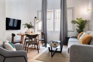 ein Wohnzimmer mit einem Sofa und einem Tisch in der Unterkunft Suites Maestranza - Santas Patronas by Magno Apartments in Sevilla