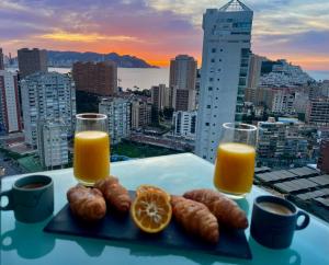 a plate of food with orange juice and croissants at Traveler's Beach Apartment with sea view, free coffee & parking in Benidorm