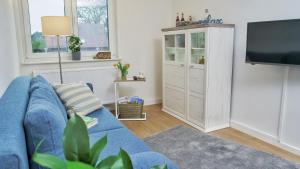 a living room with a blue couch and a tv at Quartier3 in Zeven +1 photo