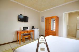Dormitorio con cama, escritorio y TV en Eagles Nest Guesthouse, en Eshowe