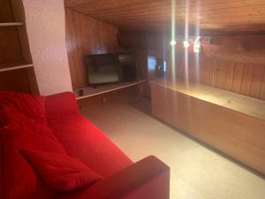 a living room with a red couch and a tv at Le p'tit coin montagne 2 in Bonneval-sur-Arc