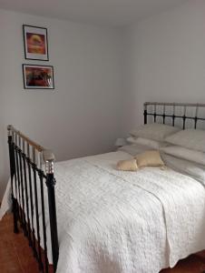 um quarto com duas camas com lençóis brancos e uma imagem na parede em Casa Rural Olivares em Villanueva de Algaidas