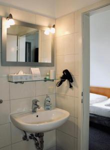 a bathroom with a sink and a mirror and a bed at Hotel & Gastro Adler GmbH in Itzehoe