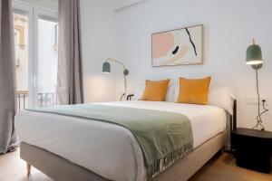 ein Schlafzimmer mit einem großen weißen Bett mit orangefarbenen Kissen in der Unterkunft Suites Maestranza - Santas Patronas by Magno Apartments in Sevilla