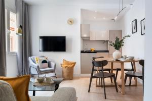 ein Wohnzimmer mit einem Tisch und Stühlen in der Unterkunft Suites Maestranza - Santas Patronas by Magno Apartments in Sevilla
