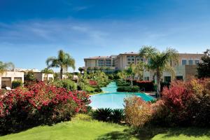 a resort swimming pool with palm trees and flowers at Regnum Carya in Belek
