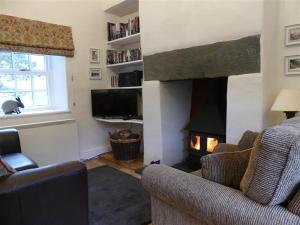 a living room with a fireplace with two chairs and a television at Pant Glas in Penmaen-mawr