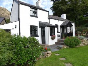 a white house with black windows and a yard at Pant Glas in Penmaen-mawr