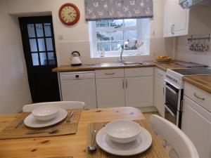 a kitchen with a table and a clock on the wall at Pant Glas in Penmaen-mawr