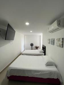 um quarto com duas camas e uma televisão na parede em Casa 145 Mirador de la Sierra em Santa Marta