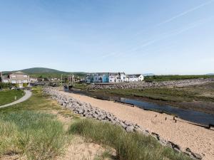 a beach with rocks and a river and houses at Lazy Cottage in Haverigg