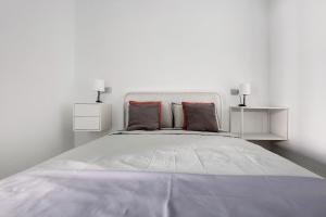 ein weißes Schlafzimmer mit einem großen Bett mit zwei Nachttischen in der Unterkunft La Corte A2 in Antigua