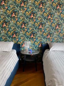 a room with two beds and a table with a wallpaper at Il cantuccio in Ivrea