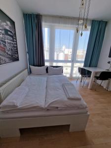 ein großes Bett in einem Zimmer mit einem Schreibtisch und Fenstern in der Unterkunft MIDTOWN Apartments in Stuttgart