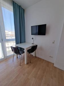 Zimmer mit einem Tisch, 2 Stühlen und einem TV in der Unterkunft MIDTOWN Apartments in Stuttgart