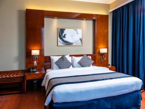 a bedroom with a large bed with blue curtains at Retaj Al Rayyan in Doha