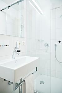 a white bathroom with a sink and a shower at Serviced Apartments by Solaria in Davos