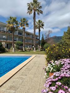 un complejo con piscina, palmeras y flores en Apartamento muy tranquilo con piscina, en Tossa de Mar
