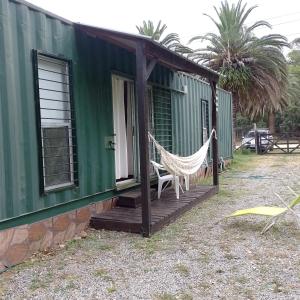 ein grünes Haus mit einer Hängematte auf einer Veranda in der Unterkunft La Chichi in Sauce de Portezuelo