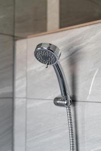 a shower with a shower head in a bathroom at Elmcroft Apartment - 10 Mins Walk to Woking Town Centre in Woking