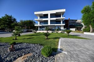 - un grand bâtiment blanc avec une cour devant dans l'établissement CROWONDER Apartments & Rooms OAZA with heated Swimming Pool and Sauna, à Turanj