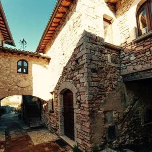 - un vieux bâtiment en pierre avec une arche à côté dans l'établissement Il borgo di Firenzuola Camere con camino, à Crocemaroggia